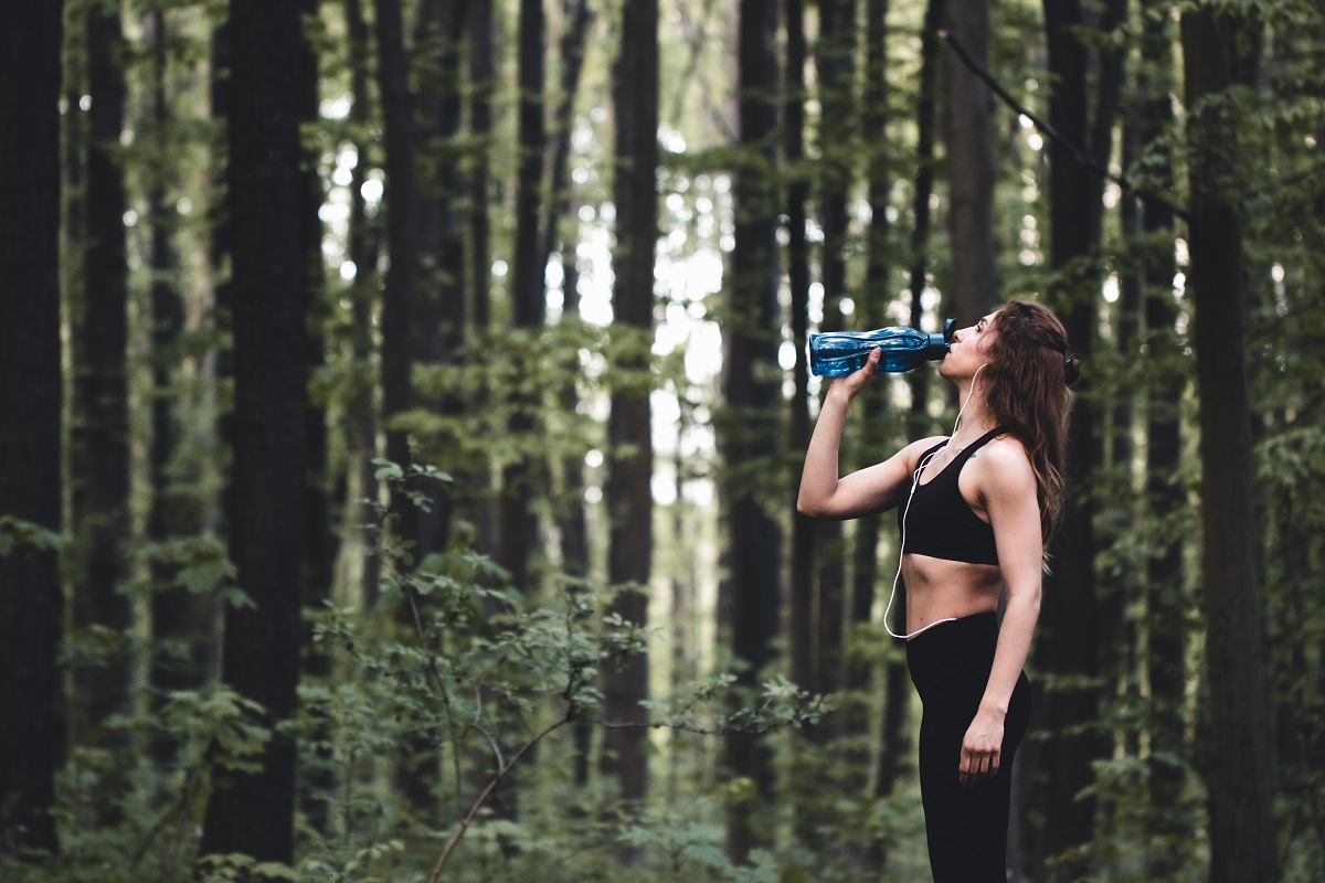 kobieta pijąca wodę w lesie